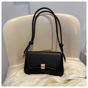 Macro view of minimalist black leather bag with gold buckle on textured fabric