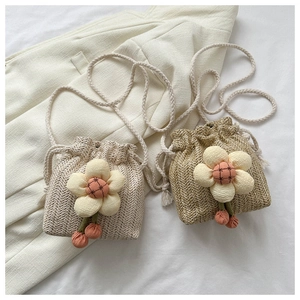 Detail of mini straw bucket bags with fabric flower decorations and braided straps