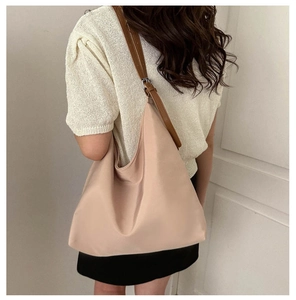 Side view of beige canvas tote bag with adjustable brown straps on model shoulder