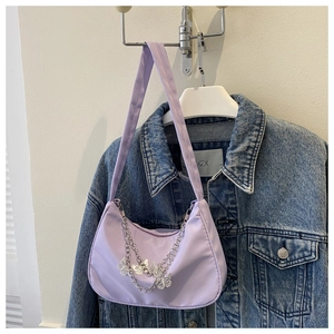 Detail of lilac satiny underarm bag featuring silver chains and butterfly charms