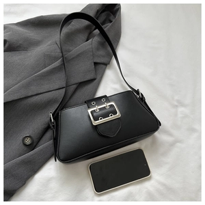Detail of minimalist black baguette bag with oversized silver metal buckle and matte finish