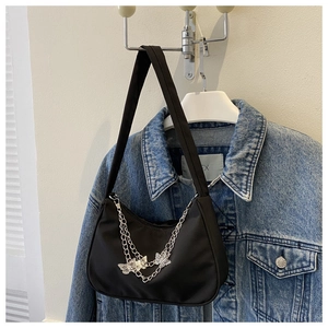 Detail of black nylon shoulder bag featuring silver metal chains and butterfly charms