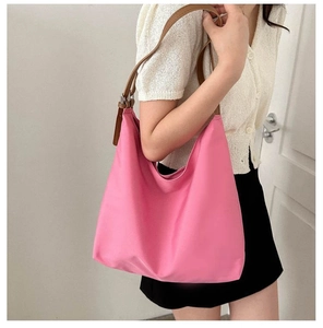 Detail view of pink canvas tote bag with brown leather straps shown on a model