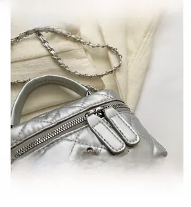 Detail view of silver quilted mini bag with camellia logo and double zip closure
