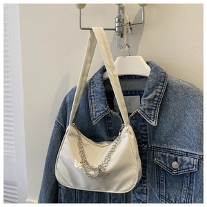 Close-up of white crescent underarm bag with silver butterfly chain and smooth leather texture