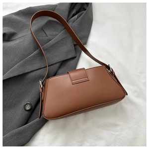 Detailed view of a vintage brown leather underarm bag on a stylish blazer background