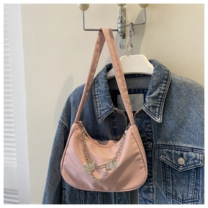 Pink crescent underarm bag with silver butterfly chain and strap on a blue denim jacket