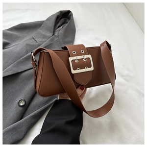 Close-up of retro brown underarm bag with large metal buckle and adjustable shoulder strap