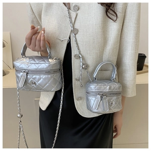 Detail of silver quilted box bag featuring floral clasp and chain strap in two sizes