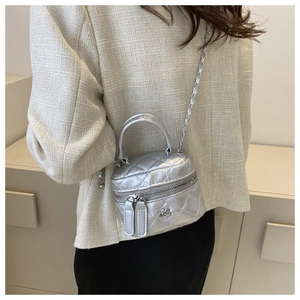 Detail showing a silver quilted leather mini box bag with chain strap worn by a model