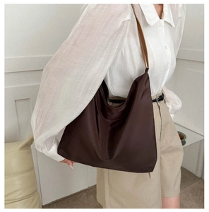 Detail of the deep brown nylon tote bag showing its smooth texture and leather handles