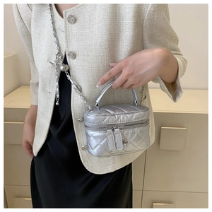 Close-up of silver quilted box bag with metal flower clasp and leather chain strap