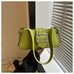 Macro view of green underarm baguette bag featuring a large silver metal buckle detail