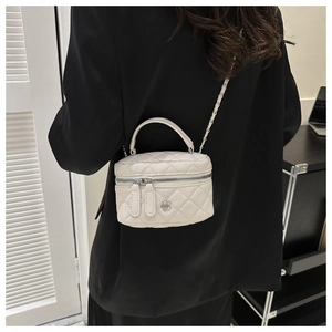 Detail of white quilted cylinder bag with silver chain strap and flower metal charm