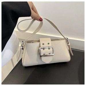 Close-up of cream underarm bag with large silver buckle and adjustable shoulder strap