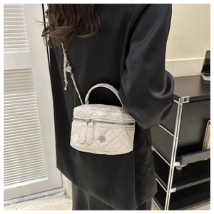 Detail of a beige quilted mini bag with silver camellia clasp and chain strap