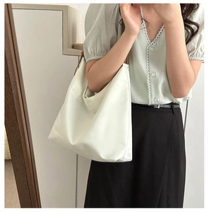 Detailed view of a white large capacity tote bag with brown straps worn over the shoulder