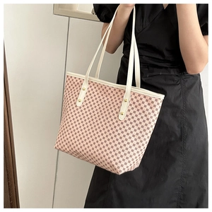 Close-up of pink monogram tote bag with cream leather straps and gold rivets