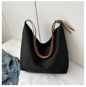 Detail of black canvas tote bag with adjustable brown leather strap and silver buckle