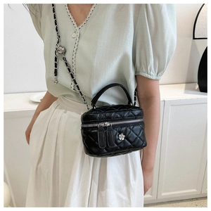 Detail of black quilted box bag with silver flower charm and leather chain strap on model