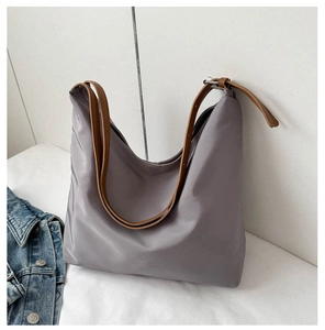 Detail of grey nylon hobo bag with brown leather straps and adjustable metal buckle