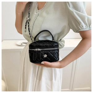 Detail of a black quilted leather mini box bag featuring silver floral hardware and chain