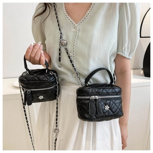 Detail of black quilted leather box bag with metal ball chain and floral charm