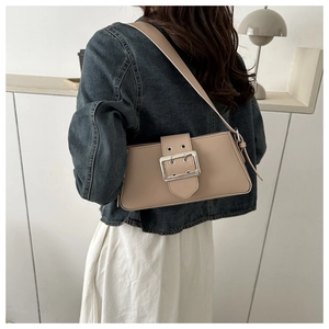 Detail of minimalist beige underarm bag with large silver buckle worn by a model
