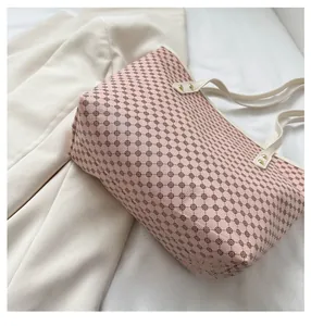 Detailed view of pink patterned tote bag with cream leather straps and gold rivets
