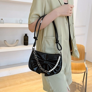 Chic black crescent shoulder bag with large bow and elegant pearl chain detail