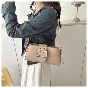 Detail of minimalist beige baguette bag featuring a wide strap and oversized silver buckle