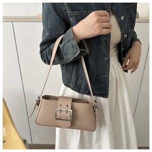 Detail of minimalist beige underarm bag with silver buckle on model in denim outfit