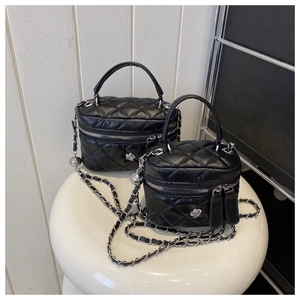 Detail of silver camellia logo on black quilted leather mini box bags with chain straps