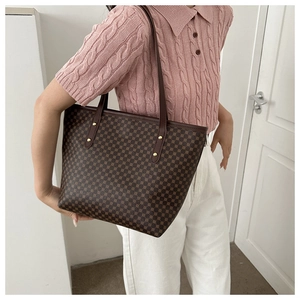 Brown tote bag with geometric circular patterns worn by model with a pink knit top