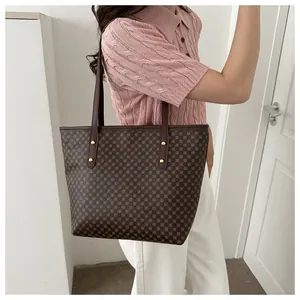 Close-up of brown geometric polka dot tote bag with leather strap and gold rivet details