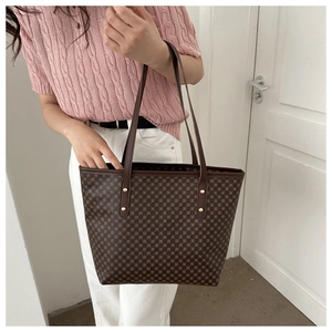 Detail of dark brown tote bag with light brown polka dots and gold rivet accents