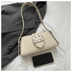 Detail of minimalist beige underarm bag with silver buckle and adjustable shoulder strap