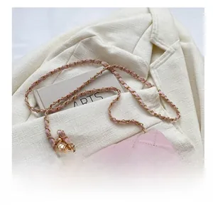 Detail einer rosa gesteppten Umhängetasche mit goldenem Drehverschluss und Kettenriemen