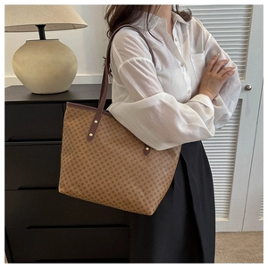 Detail of a brown geometric pattern tote bag with leather straps and gold metal buckles