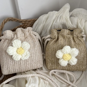 Handwoven straw bucket bag with oversized floral accents and drawstring shoulder strap
