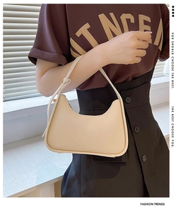 Dettaglio di una borsa a mezzaluna beige con tracolla regolabile e cerniera dorata