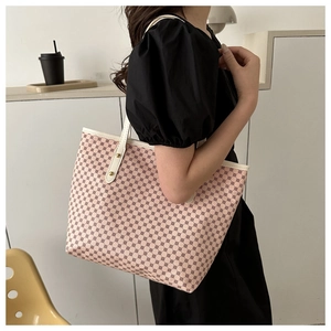 Detail of pink tote bag with red geometric circles and white shoulder strap shown on a model