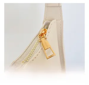 Dettaglio ravvicinato di una cerniera dorata su una borsa in pelle beige con texture