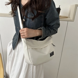 Dettaglio della borsa a tracolla in nylon bianco con patch logo e stile minimalista