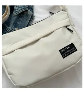 Dettaglio della borsa a tracolla in nylon bianco con etichetta su denim