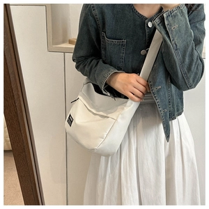 Dettaglio di una borsa a tracolla bianca in nylon con tracolla larga su una modella