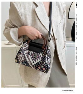 Close-up of bohemian jacquard woven crossbody bag with vintage wooden handle on a model
