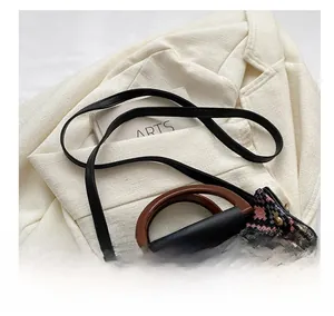 Detail of ethnic woven handbag with dark wood handles and black leather shoulder strap