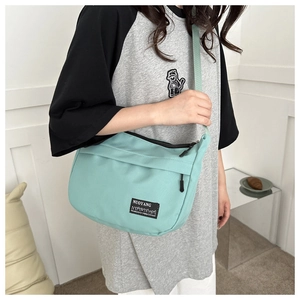 Dettaglio della borsa a spalla in nylon verde menta con trama minimalista e logo in tessuto