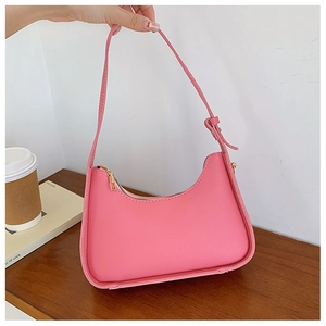 Dettaglio borsa hobo rosa con cerniera dorata e tracolla regolabile su scrivania minimal